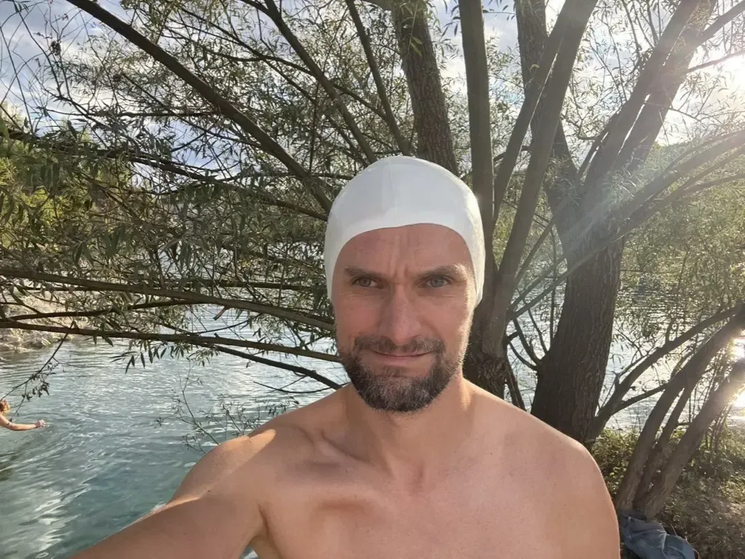 Me in a swim cap by the water between the willows, ready for a swim without the watch