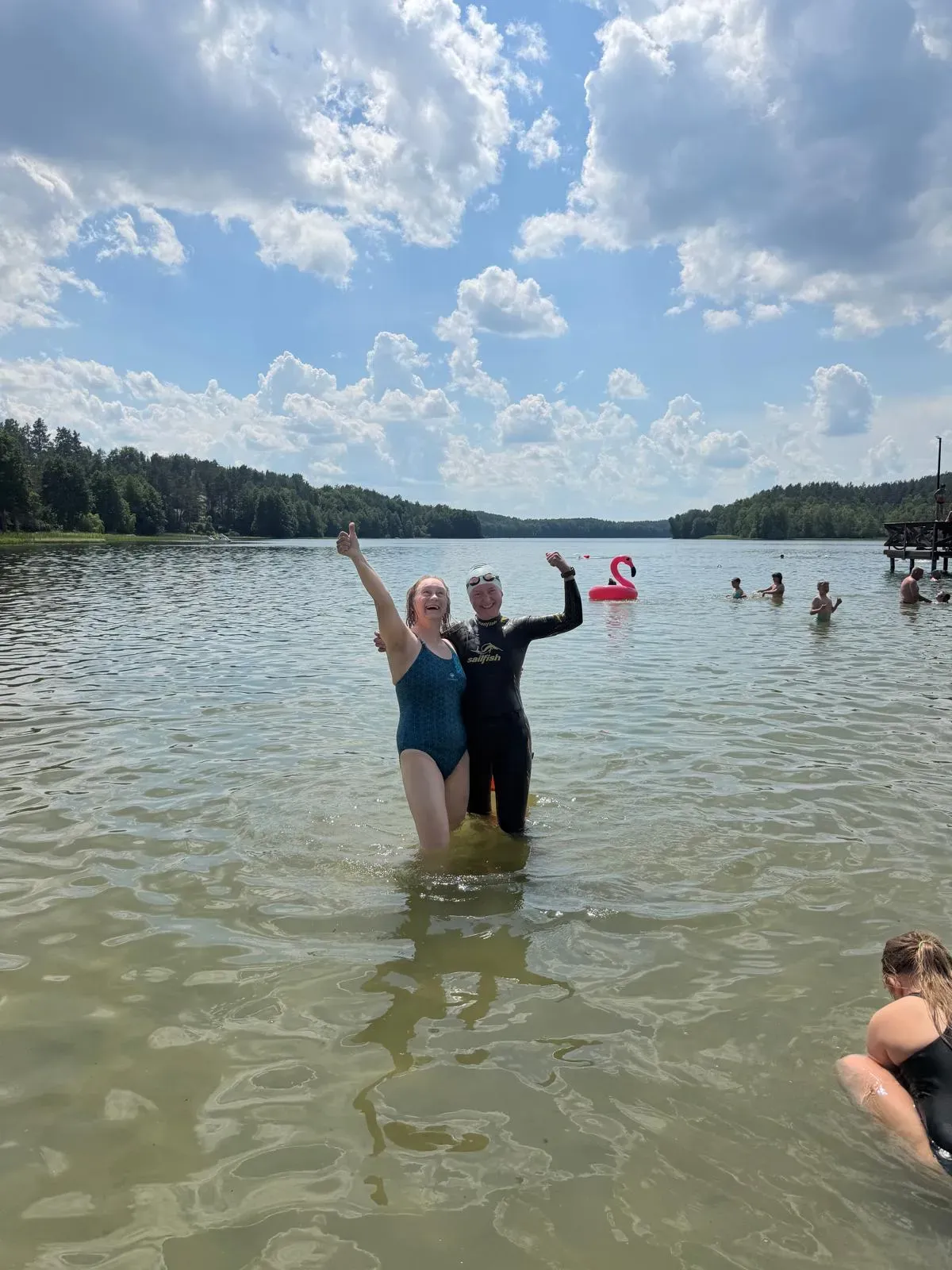 Two swimmers celebrating after the final challenge on a sunny Lake Dąbrowskie