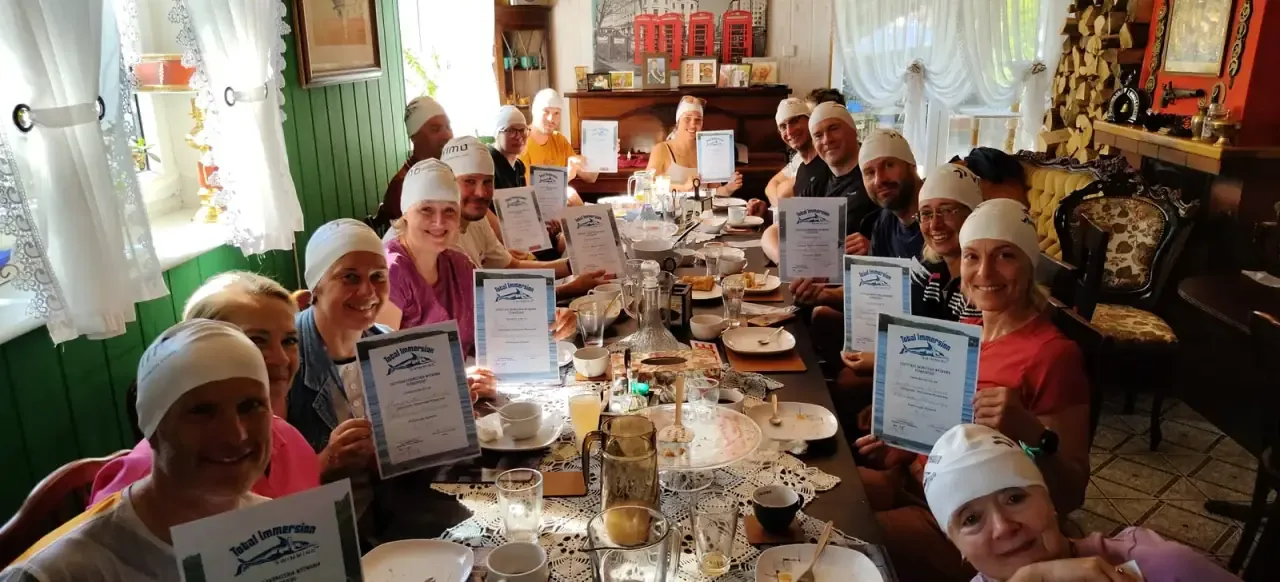 The whole group around the table with their Total Immersion certificates at the end of the camp