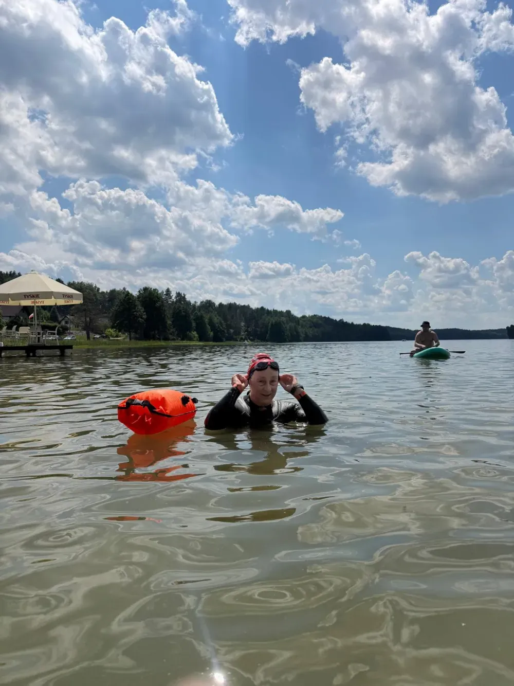 A swimmer resting on a buoy under a wide summer sky