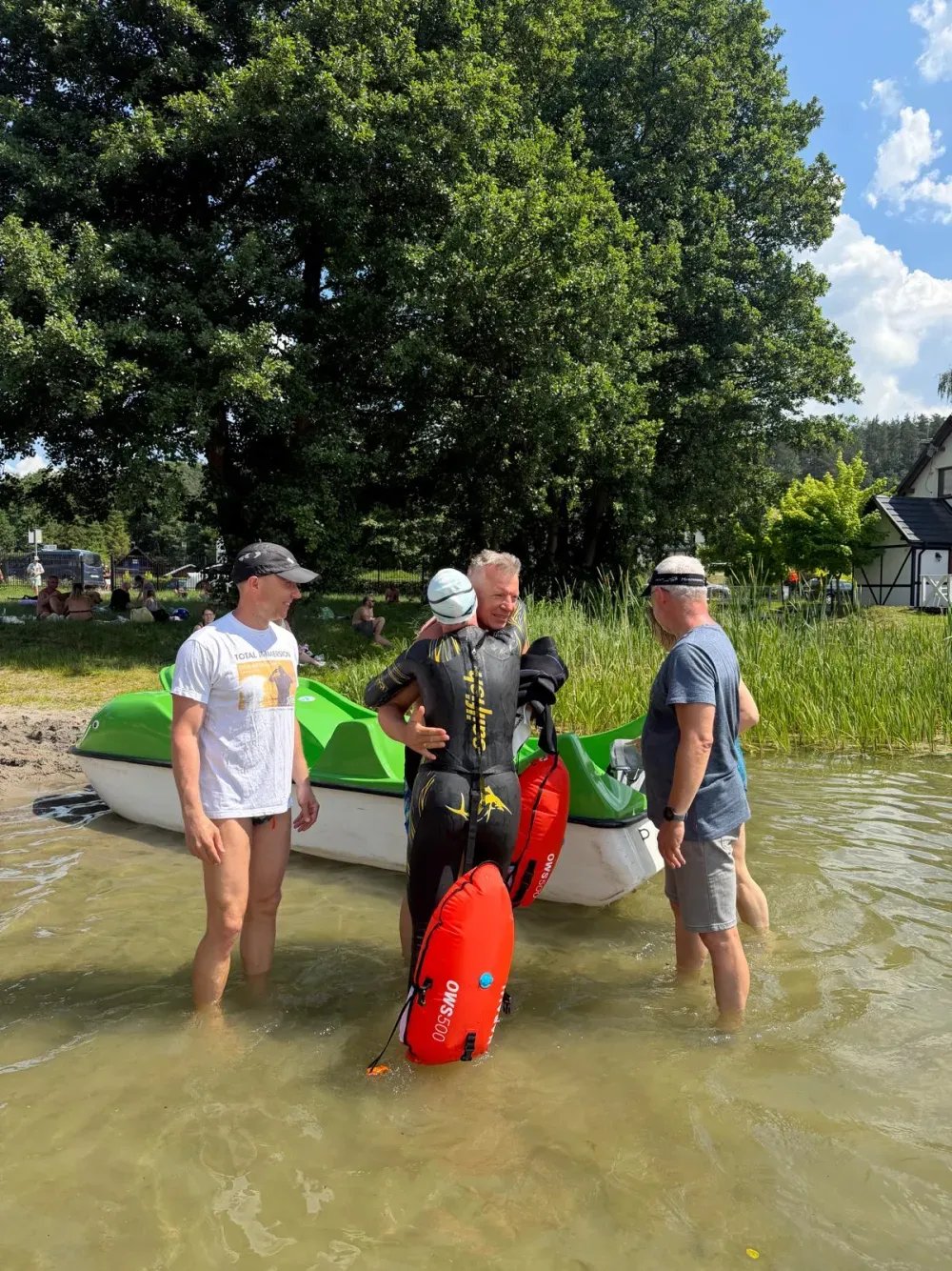 A small group by a pedal boat at the water's edge