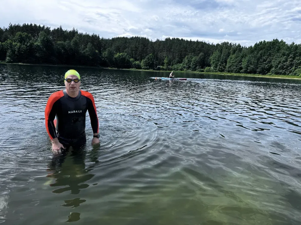 A swimmer standing in the lake with the far shore behind