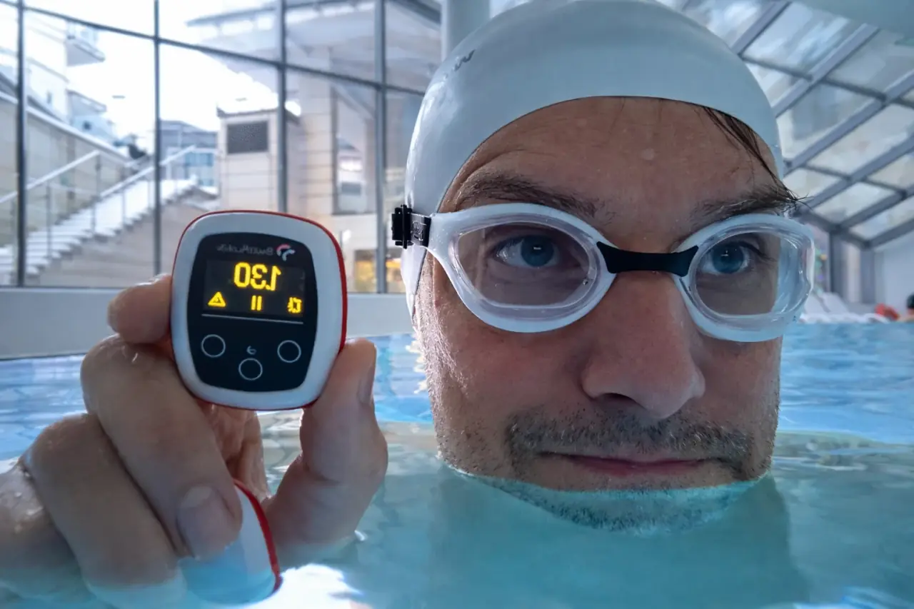 Swimmer in the pool holding a Vimo tempo trainer with the tempo on screen