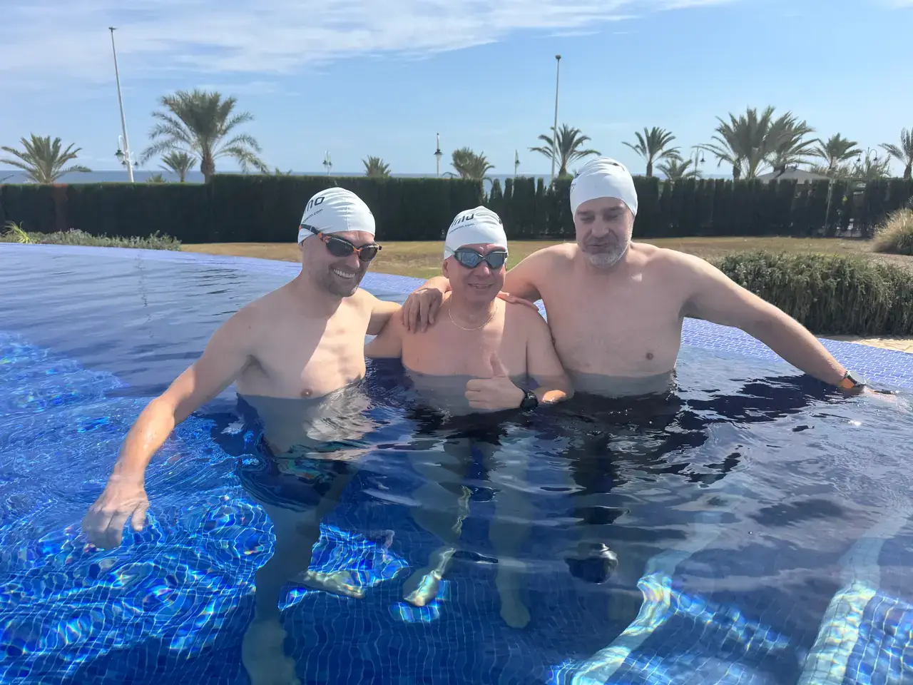 Three swimmers in Vimo caps in the pool after a session