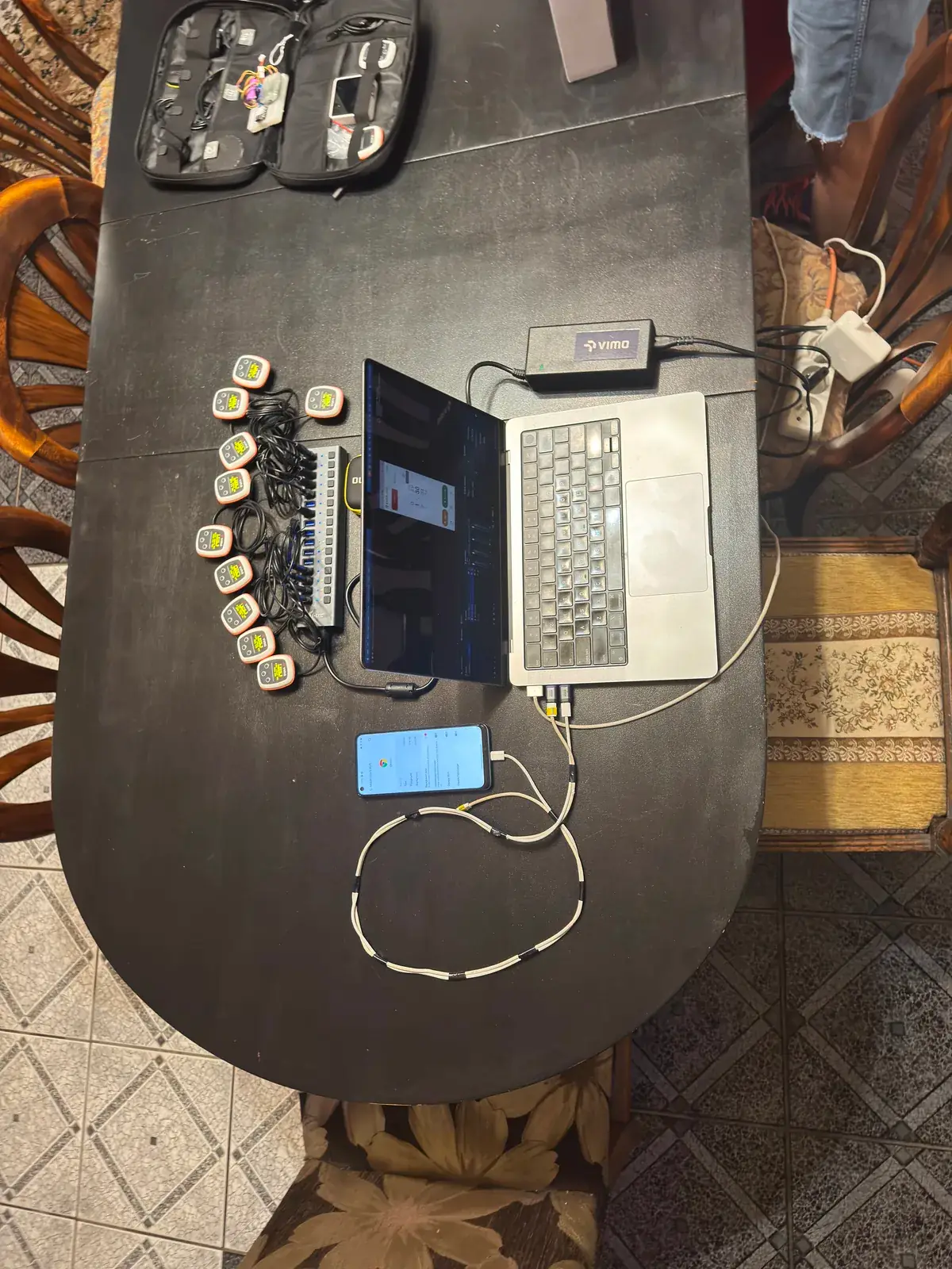 A laptop, a phone and a row of tempo trainers on a charging hub during a firmware update
