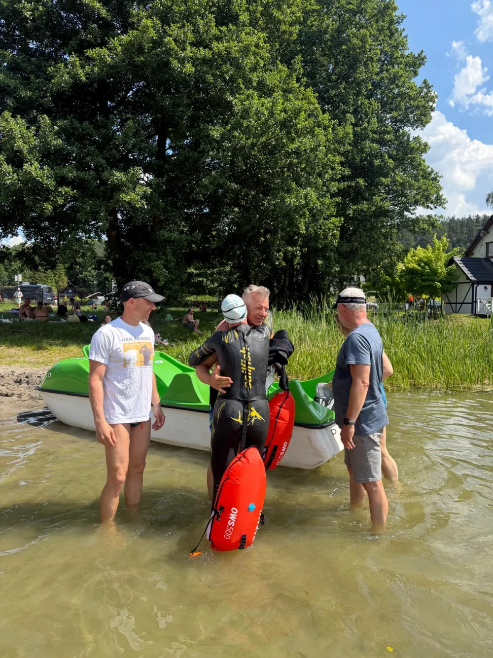 A small group by a pedal boat at the water's edge