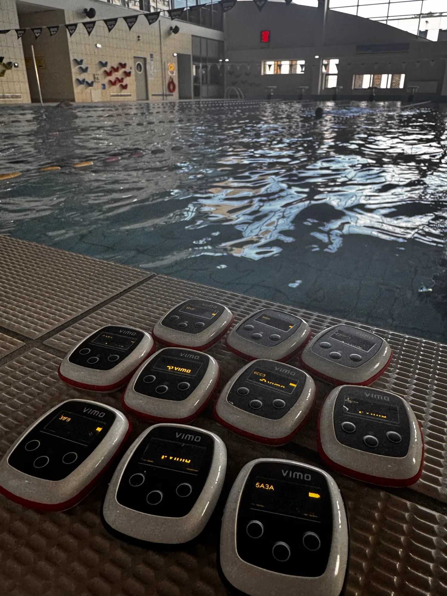 Vimo devices lined up on the poolside grating with the pool behind