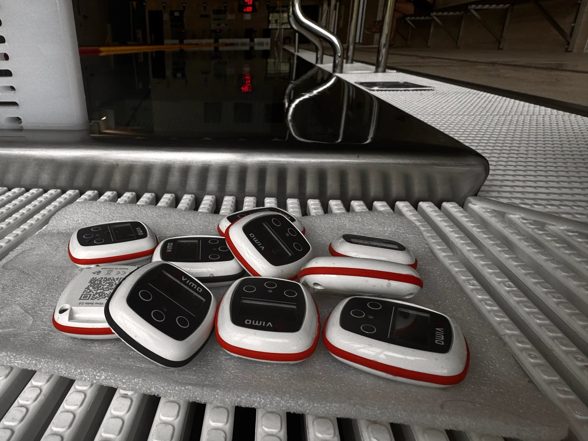 Eight Vimo devices laid out on the poolside grating next to the pool edge