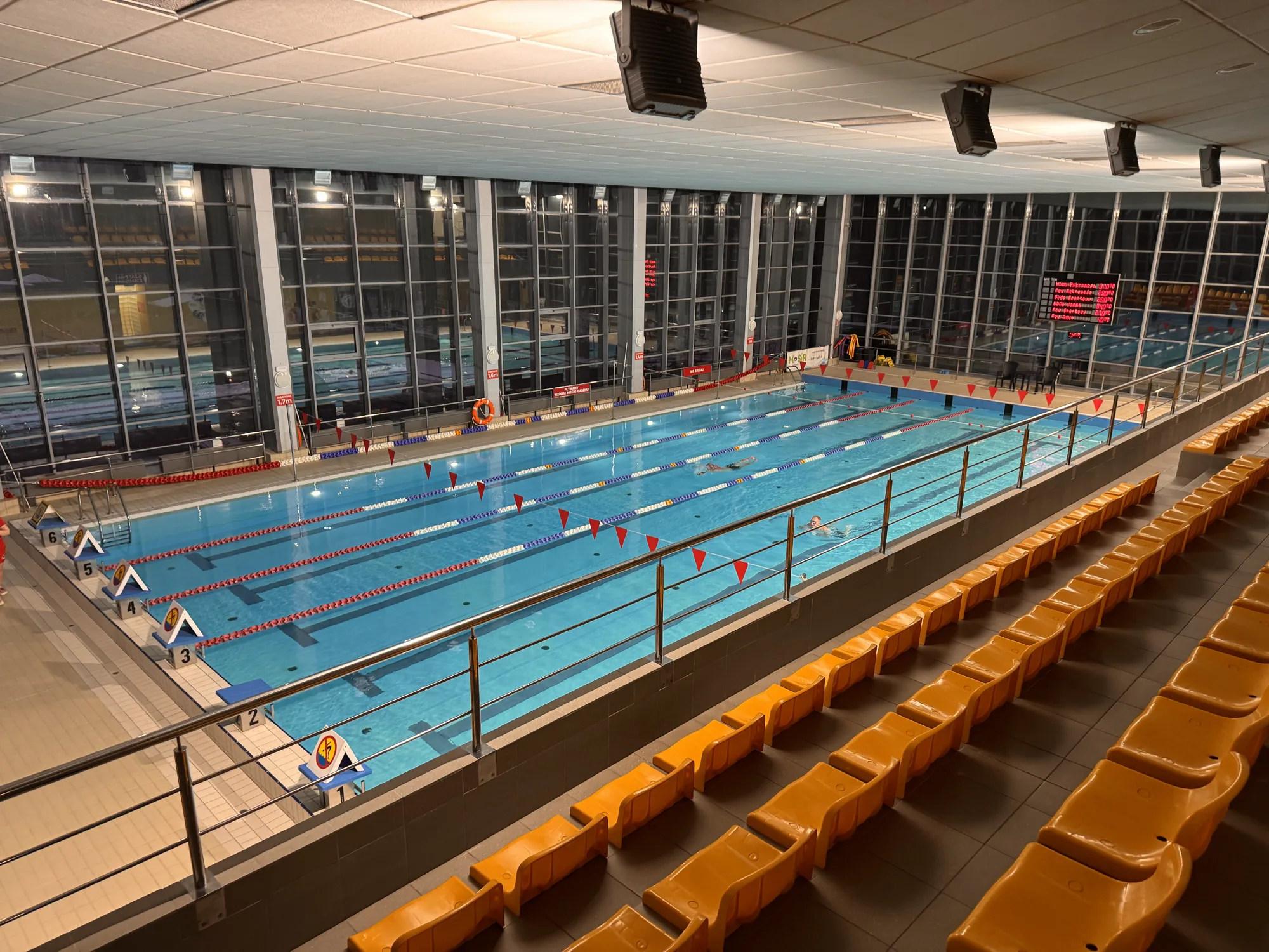Empty indoor pool with the lanes set and the seats waiting