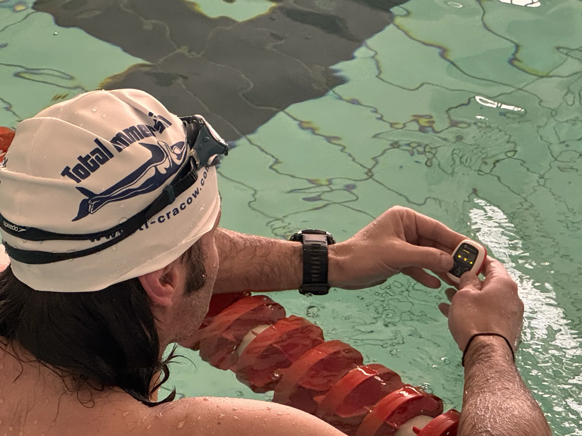 Swimmer in a Total Immersion cap setting the tempo at the lane rope